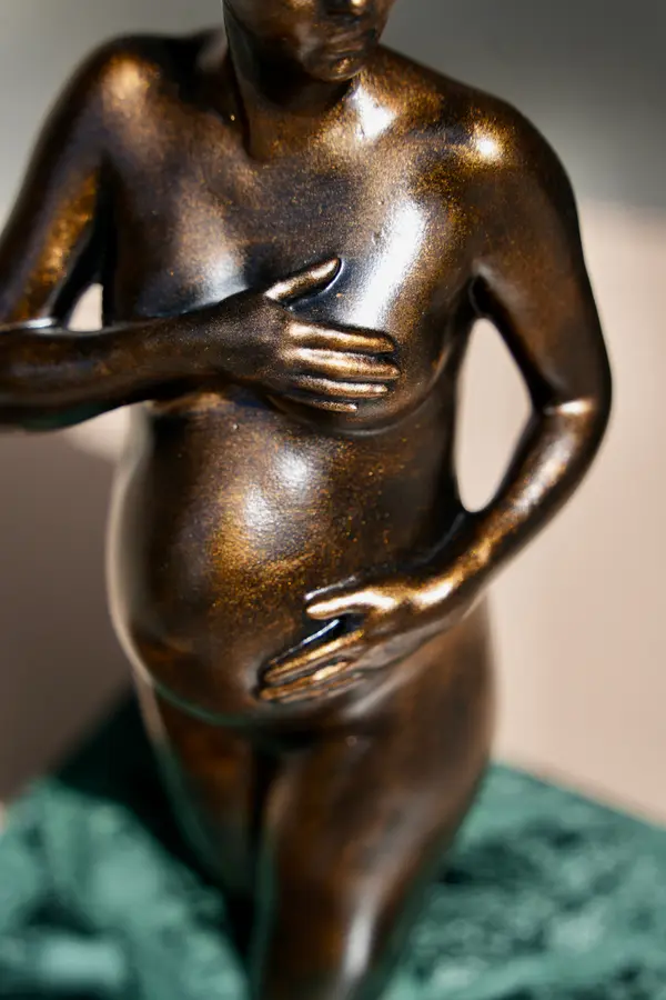 Détail d'une sculpture Arte-Lumina teinte bronze : mains sur le ventre et la poitrine